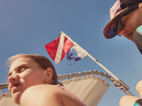 Low angle view father and daughter boating below diving flag
