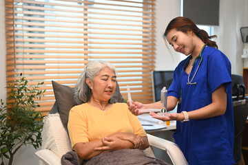 Physical therapist assisting mature woman patient doing breathing exercises with a spirometer