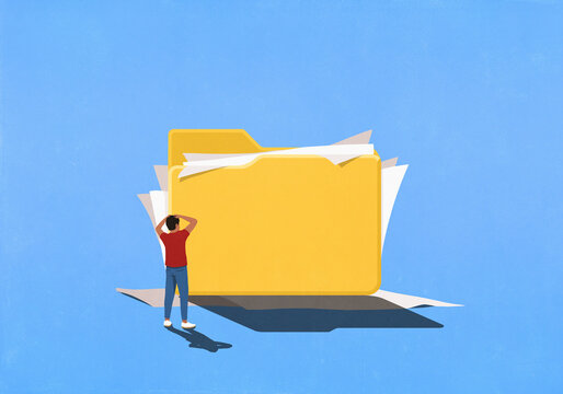 Frustrated man looking at messy paperwork spilling out of large file folder
