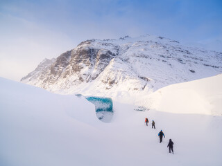 Team in front of the entrance to an ice cave in Iceland. A walk on the glacier. High mountains and...
