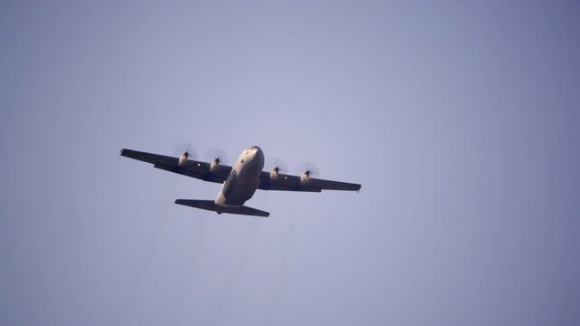 Lockheed C-130 Hercules flying overhead during tactical mission, showing its four turboprop engines and high-wing structure. The C-130 is widely used for cargo and troop transport.