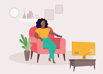 One Plus Size Black Woman With Remote Control Sitting On Sofa Watching TV In The Living Room At Home.