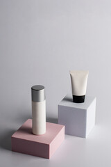 Plastic white tube for cream or lotion. Skin care or sunscreen cosmetic with stylish props on cream background.