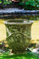 Weathered Stone Planter by Reflective Pond in Garden Setting