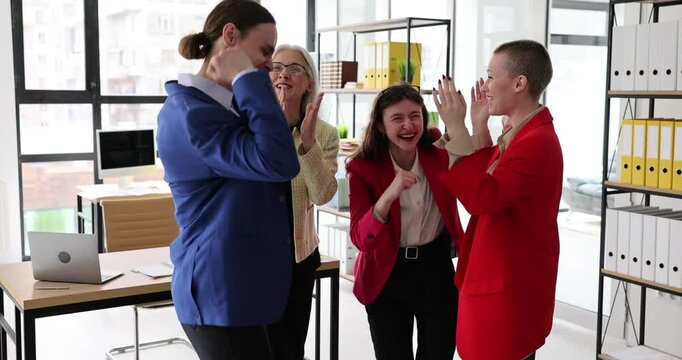 Office female employees have fun after successful business offer from company. Colleagues celebrate important proposition raising hands slow motion