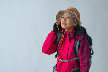 怯えてスマホで通話する登山服のシニア女性