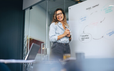 Happy caucasian business woman presenting a product flow chart to her team in a meeting