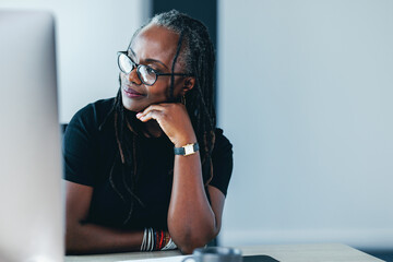 African business woman looking away with a pensive expression in her office