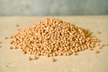 A pile of raw chickpeas placed on a light surface.