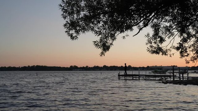 A silhouette of a man looking at a lake during sunset in Michigan