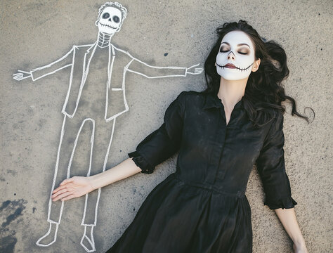 An attractive woman in a black dress, with white face paint, lies on the floor next to a chalk outline of a human body.
