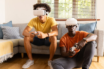 At home, Playing video games, two diverse male friends wearing VR headsets and holding controllers