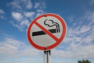 No smoking sign against blue sky, mounted on metallic pole