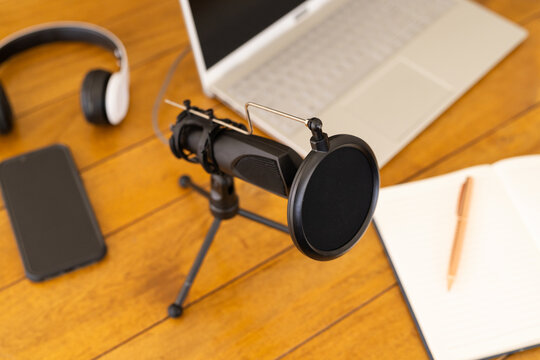 Close-up, At home, Podcasting setup with microphone, laptop, headphones, smartphone, and notepad on 
