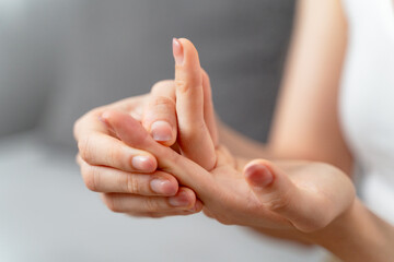 Closeup young woman sitting on sofa holds her wrist. hand injury, feeling pain. Health care.