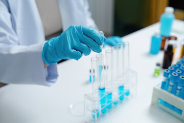 Fototapeta premium Scientist Conducting Experiment with Test Tubes in Laboratory Wearing Blue Gloves