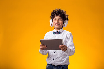 Child boy using digital tablet and headphones and playing video game. Leisure and gadget addiction concept