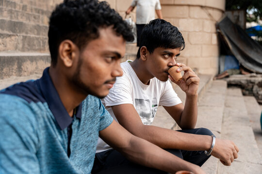 Indian young man sipping chai tea sitting next to friend - Powered by Adobe