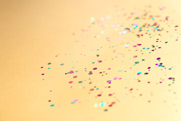 Colorful of confetti on gold background. Brilliant colored sequins. Holiday greeting card. Happy holidays. Minimal, flat lay, copy space. Mockup	