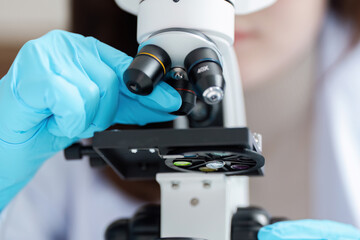 Scientist Adjusting Microscope in Laboratory with Blue Gloves for Scientific Research and Analysis