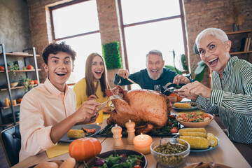 Photo of friendly sweet family cutting turkey excited eating thanksgiving holiday dinner smiling...
