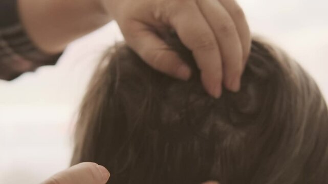 Close-up child's head, Mother's hands applying lice and nit treatment in hair, treating with medication, regular hygiene and pest control, Pediculosis