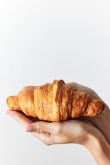 Person holding a croissant in close up shot on white background