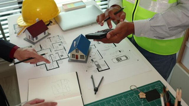 Two engineers are having a meeting about a problem have made the proportions of the house unsafe, architect and contractor are having a final meeting before finalizing the blueprints for construction.