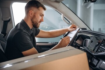 Obraz premium Writing in the notepad document. The delivery man or a loader is in the car with box