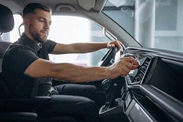 View from the side. Man is sitting in the car, driver