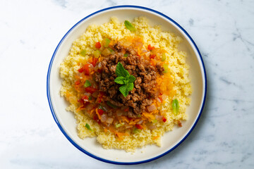 Couscous salad with vegetables and minced meat. Top view table with decoration.