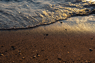 Waves lap the seashore and cover the small stones.
