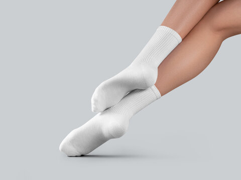 Mockup of white long socks on women's legs, with stretched toes, diagonal presentation, back view, isolated on background.