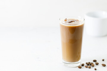 Ice coffee in a tall glass with milk on white marble table.