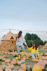 woman and daughter having fun with farming on a pumpkin patch. thanksgiving and halloween concept.