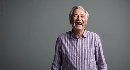 Obraz premium Laughing elderly Caucasian man wearing plaid shirt on plain grey background