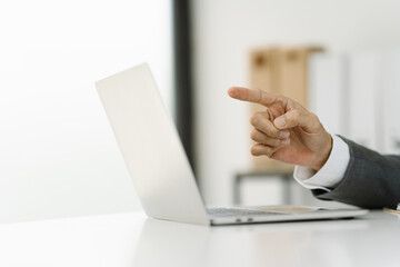 Strategic Pointing: Close-up of a businessman's hand pointing at a laptop screen, suggesting insightful analysis, digital strategy, or a key business decision.