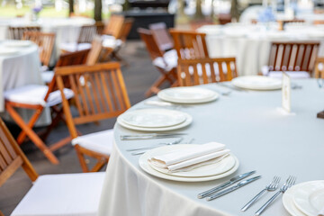 Beautifully organized event - round served table banquet ready for guests, round decorated table with empty plate, glasses, forks, napkin.