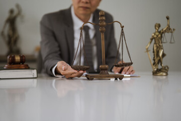 Justice and Scales of Balance: Lawyer reviewing documents with scales of justice and gavel in background.  A symbolic image representing law, fairness, and legal proceedings. 