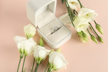 Beautiful ring with gemstone in box and flowers on pink background