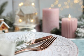 Christmas place setting with plate, cutlery and festive decor on table, closeup