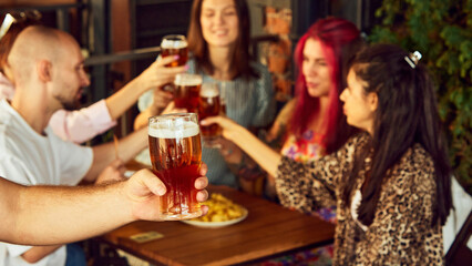 Glasses raised high, fans immerse themselves in energy of game, savoring every sip and every moment. Selective focus. Concept of Oktoberfest, brewery, vacation, Friday mood.