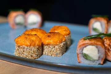 Close-up of the chef putting baked sushi rolls on a plate.