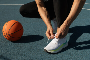 Close up basketball player tying sports shoes in basketball court outdoors. Last preparation....