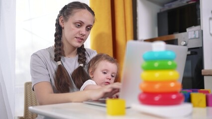 Mom works and lifestyle looks after the child. happy childhood dream concept for a little child. young mother works remotely via laptop during quarantine and plays with blocks with her small child