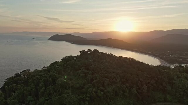 Aerial view zoom in sun on Juquehy Bay at sunset sunrise with mountains and trees