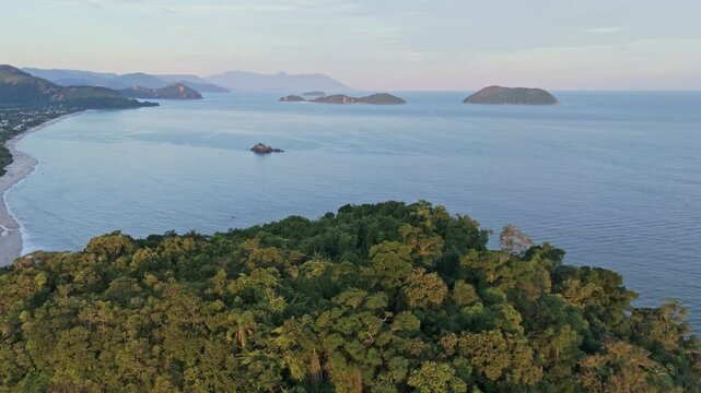 Aerial view semi orbit on Juquehy Bay at sunset with mountains and trees