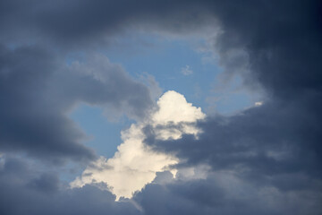 
a pale white cloud among dark clouds
