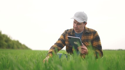 farmer works in the field. technology people and nature concept. farmer in a plaid shirt and with a...
