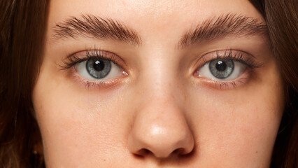 Fototapeta premium Close-up of blue eyes with neatly groomed eyebrows, highlighting natural beauty and facial care. Young female model with well-kept skin. Concept of beauty, fashion, appearance, self care. Ad
